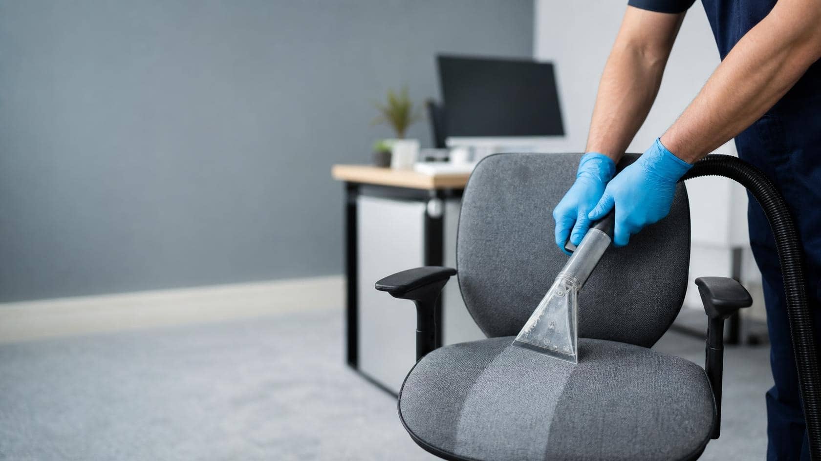 A cleaner using an upholstery extraction tool on a fabric office chair