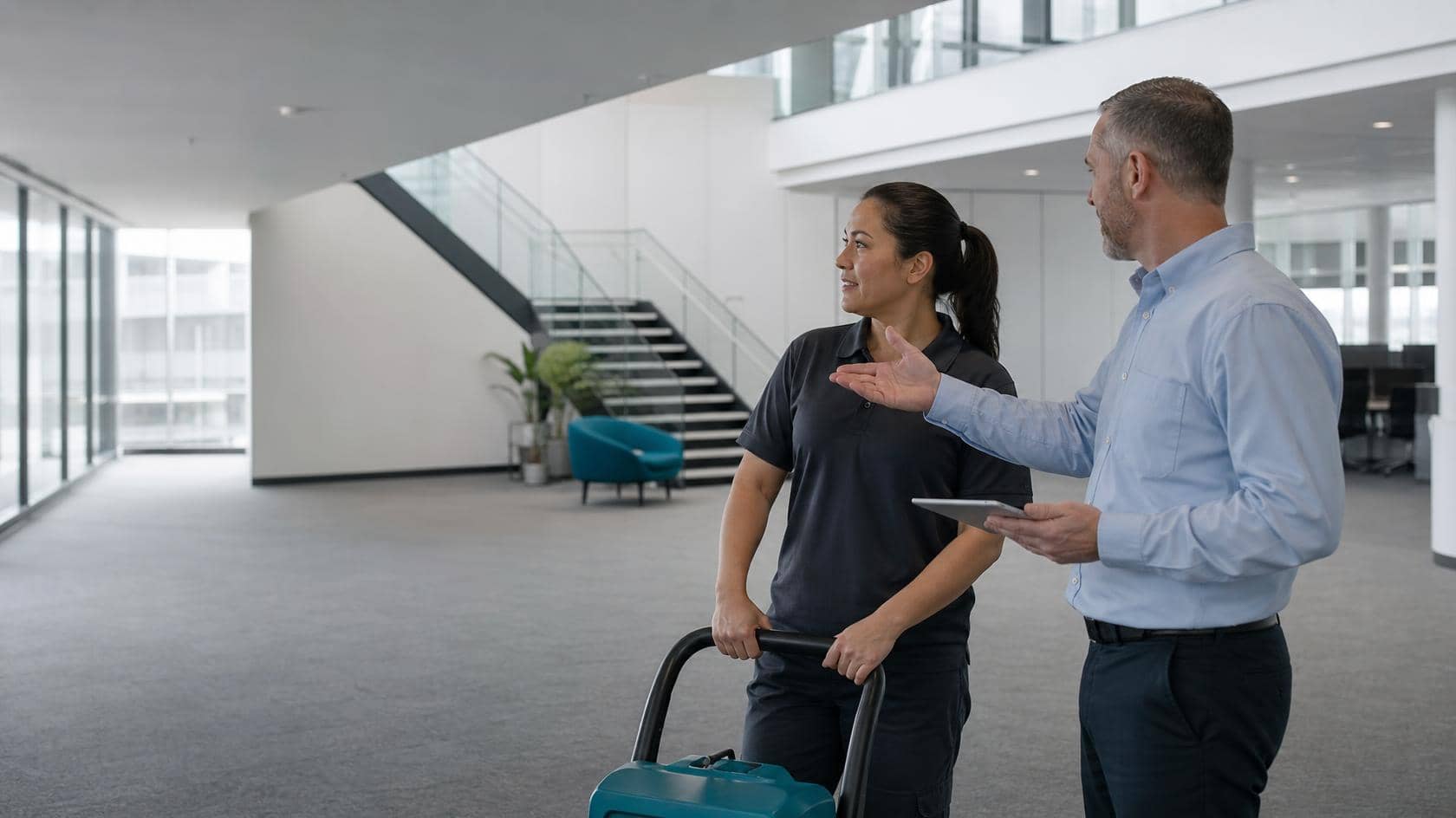A Magic Hands cleaner and a facilities manager talking together in a bright commercial office foyer